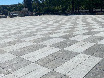 Large plaza paved in Rammer Grey granite 30×15×3 cm — sawn-edge, sandblasted pavers for clean modern grids.