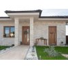 Stone bricks Travertine Classic covering the front entrance facade of a modern family house with natural beige tones.