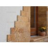 Stone siding Travertine Gold highlighting entrance steps with light-reflecting natural texture.