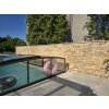Stone wall cladding Travertine Gold used as elegant poolside wall with warm golden tones.