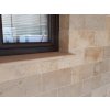 Outdoor pavers Travertine Noche 30×15×3 cm, wall/facade cladding under a window with rustic hand-chiselled edges.