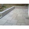 Paving slabs in Sandstone Greyl Roman pattern finish a raised terrace corner beside the house.