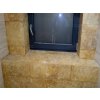 Bathroom stone tiles Travertine Gold CC show a close-up of golden travertine surface around a window ledge.
