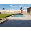 Travertine Classic French pattern surrounding a backyard swimming pool with lawn, overall look.