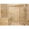 Walk-in shower with bench clad in Travertine Classic Beige Premium VC large-format tiles, unfilled and honed.