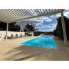 Pergola area by the swimming pool paved with beige natural stone – Marble Shells Beige, honed large-format tiles.