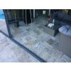 Natural stone patio with Travertine Silver French pattern; detail near sliding doors and seating area.