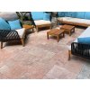 Stone patio with Travertine Red French pattern tumbled tiles, cozy outdoor seating set on a shaded veranda.