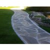 Garden walkway made of natural Sandstone slabs in soft earthy shades with rough surface texture.
