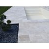 Garden patio slabs of Travertine Classic placed around a backyard pool, close view of the rectangular layout by the lawn.