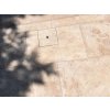 Paving slabs in Travertine Noche with a neat service/utility cover detail, showing the warm brown-beige stone texture.