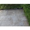 Garden patio slabs of Travertine Noche set beside a hedge, even surface with access hatch integrated in the layout.