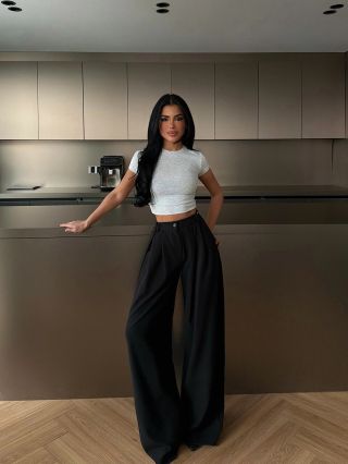 Vysoký pas, široké nohavice a silueta, která prodlužuje postavu. Černá klasika, která funguje s topem i sakem bez...