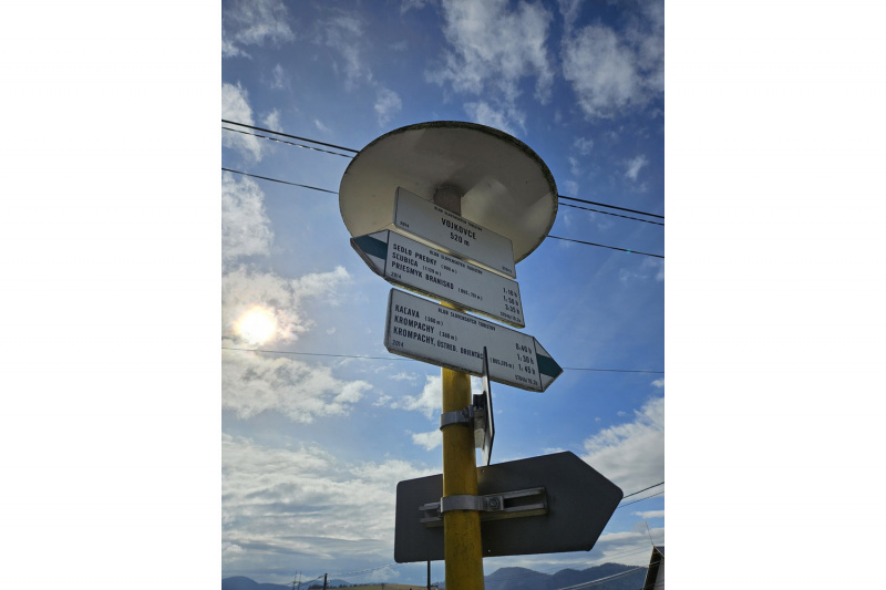 Turistický smerovník na začiatku trasy v obci Vojkovce.