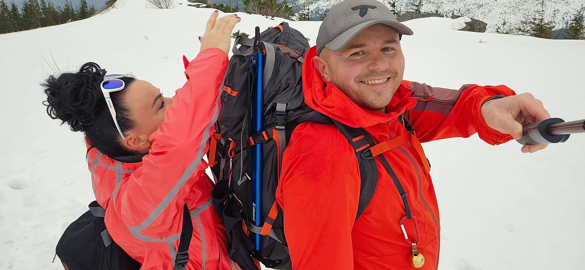 Turista v zimnom oblečení hľadajúci veci v batohu počas veternej túry na Kráľovej holi.