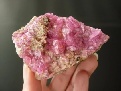 kobaltový kalcit minerál držený v prstech