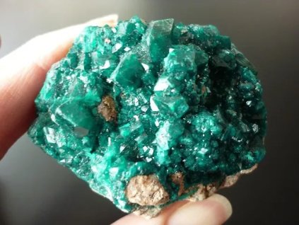 dioptas minerál držený v prstech