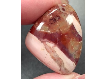 opál růžový minerál držený v prstech detail