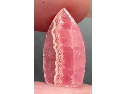 minerál rodochrozit držený v prstech detail