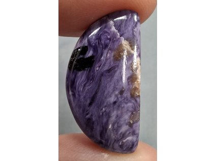 čaroit minerál držený v prstech detail