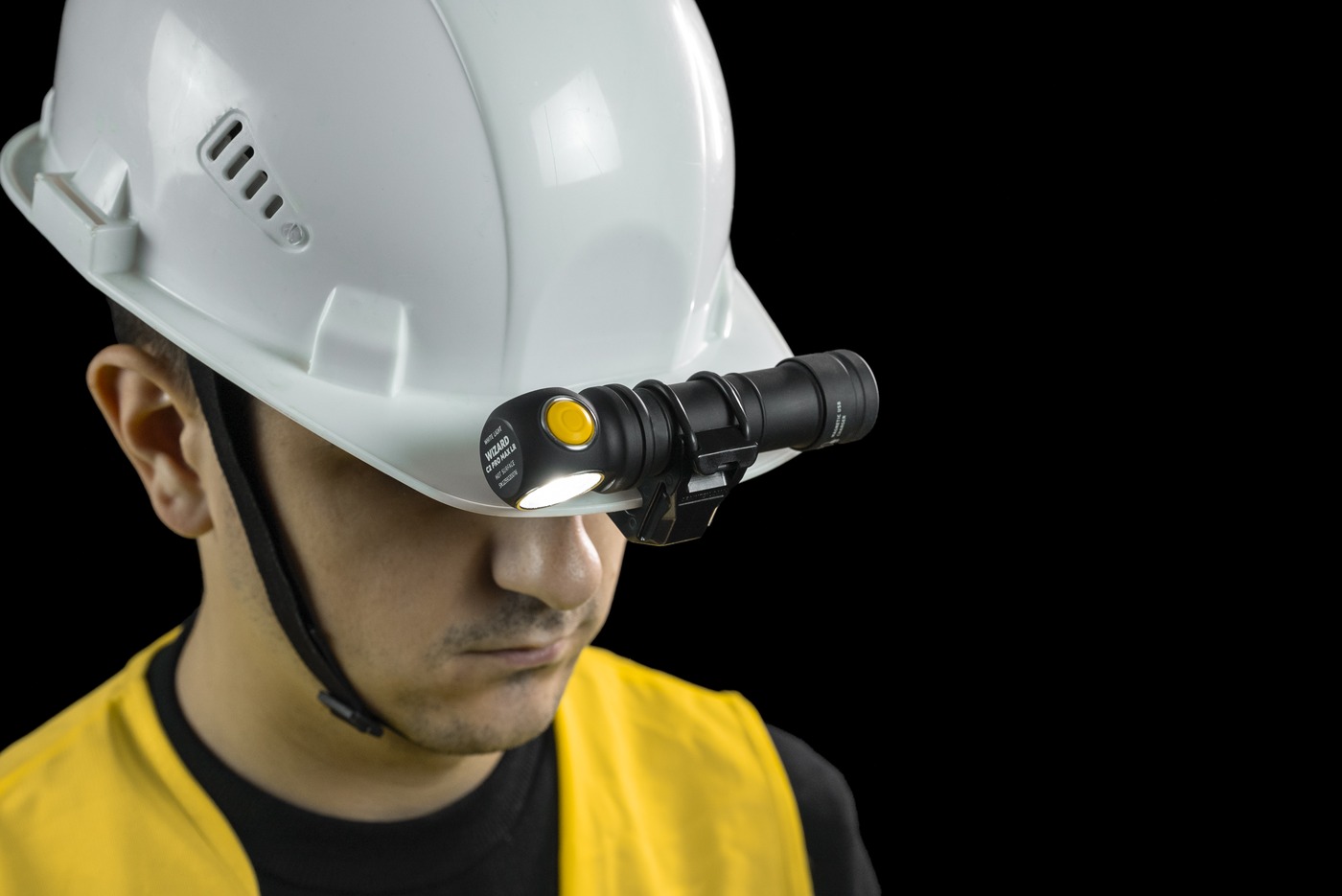 Armytek Wizard C2 Pro Max LR s telom 23,6 mm v držiaku AHM-04 na šilte prilby, lúč smeruje nadol pred pracovníka