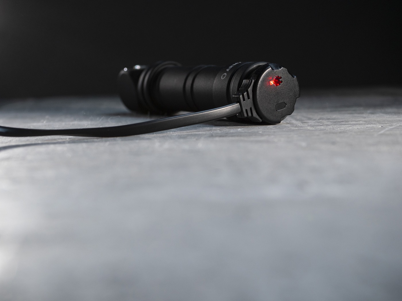Armytek AMC-02 na svetle Wizard C2 Pro Max, nabíjacia koncovka na chvoste so svietiacou červenou kontrolkou