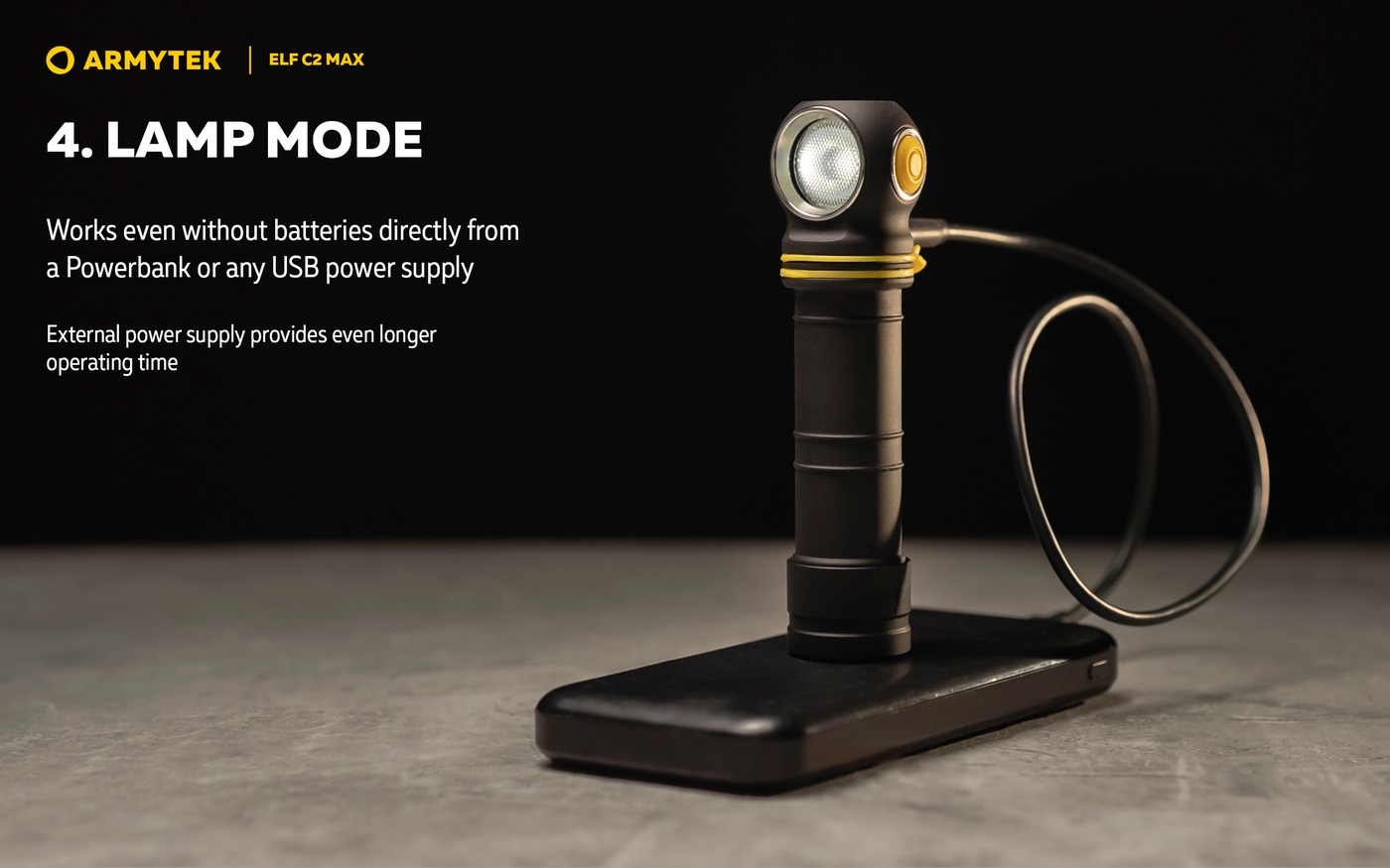 Čelovka Armytek Elf C2 Max stojí na powerbanke a svieti v režime lampy, kábel USB-C zapojený z boku hlavy