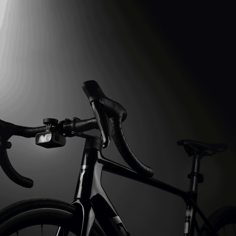 Magicshine HORI 1300 PRO na riadidlách cestného bicykla svieti v tme — technológia FTR LightSync