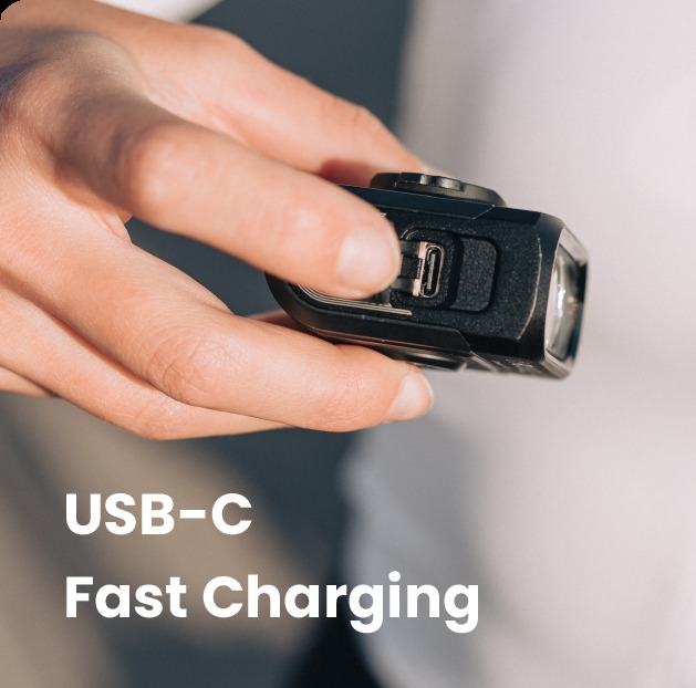 Odklopen&yacute; gumen&yacute; kryt nab&iacute;jacieho portu USB-C na tele Magicshine HORI 900 držan&eacute;ho v ruke