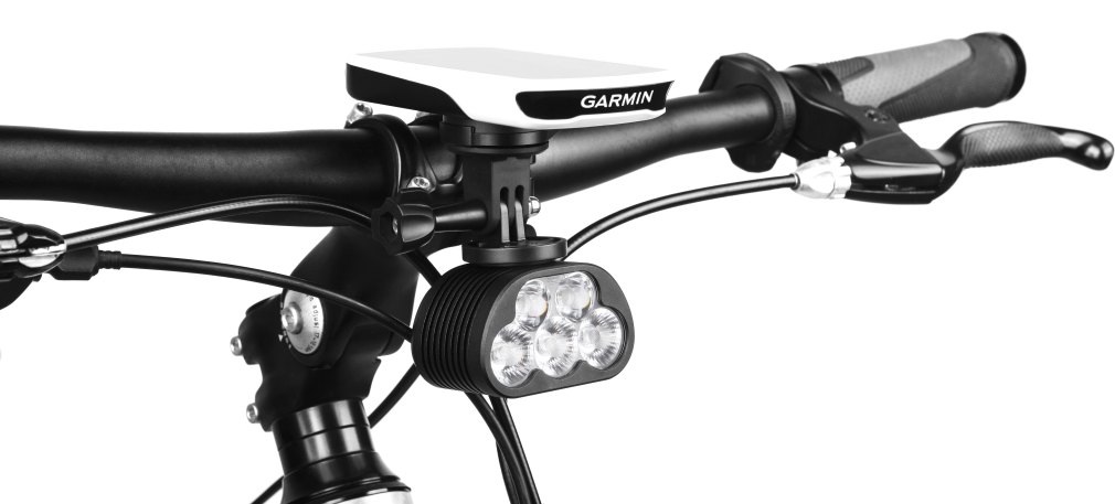 Cyklopočítač na predsadenom držiaku a pod ním svietidlo Magicshine zavesené cez GoPro adaptér