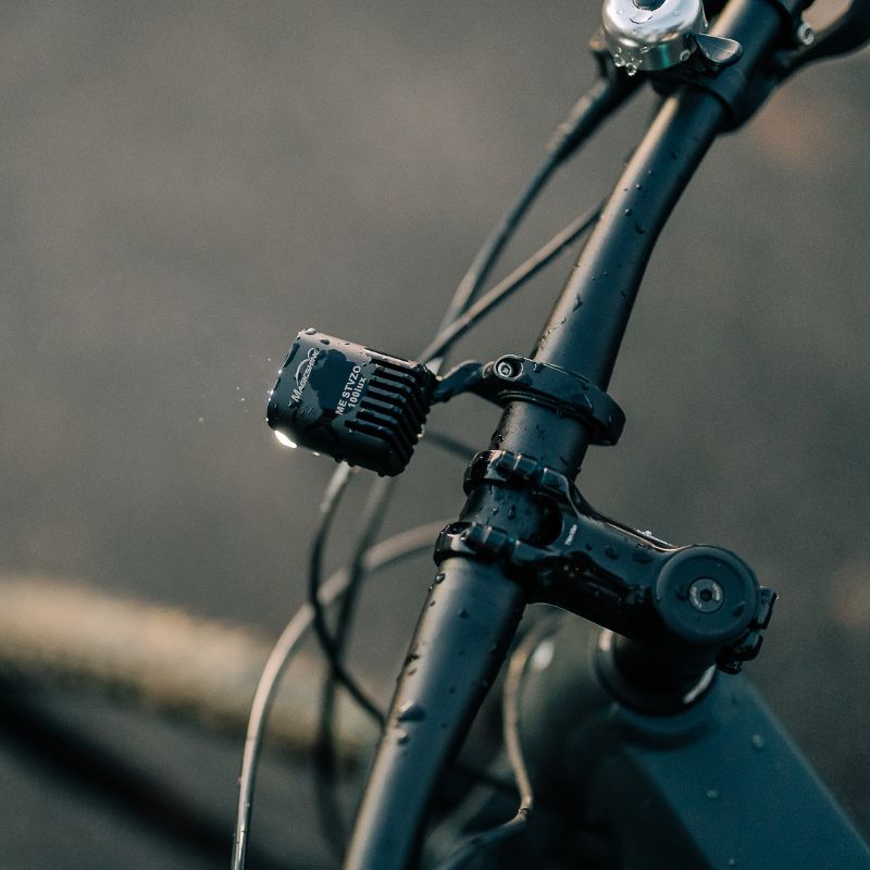 Magicshine ME StVZO 100LUX zhasnutý na predstavci elektrobicykla, celý pokrytý kvapkami dažďa