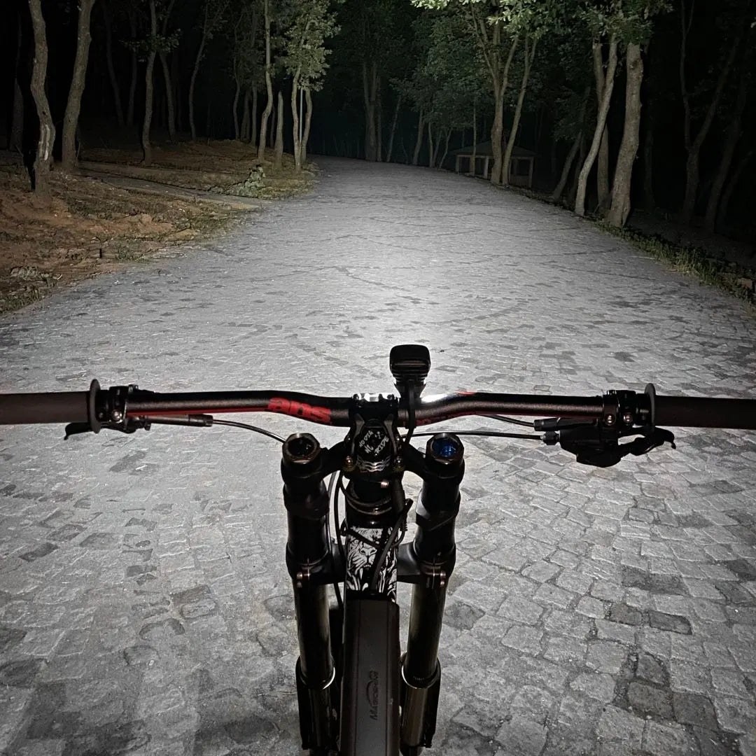 Pohľad z riadidiel bicykla na nočný lesný chodník osvetlený svetlom Magicshine MJ-906S