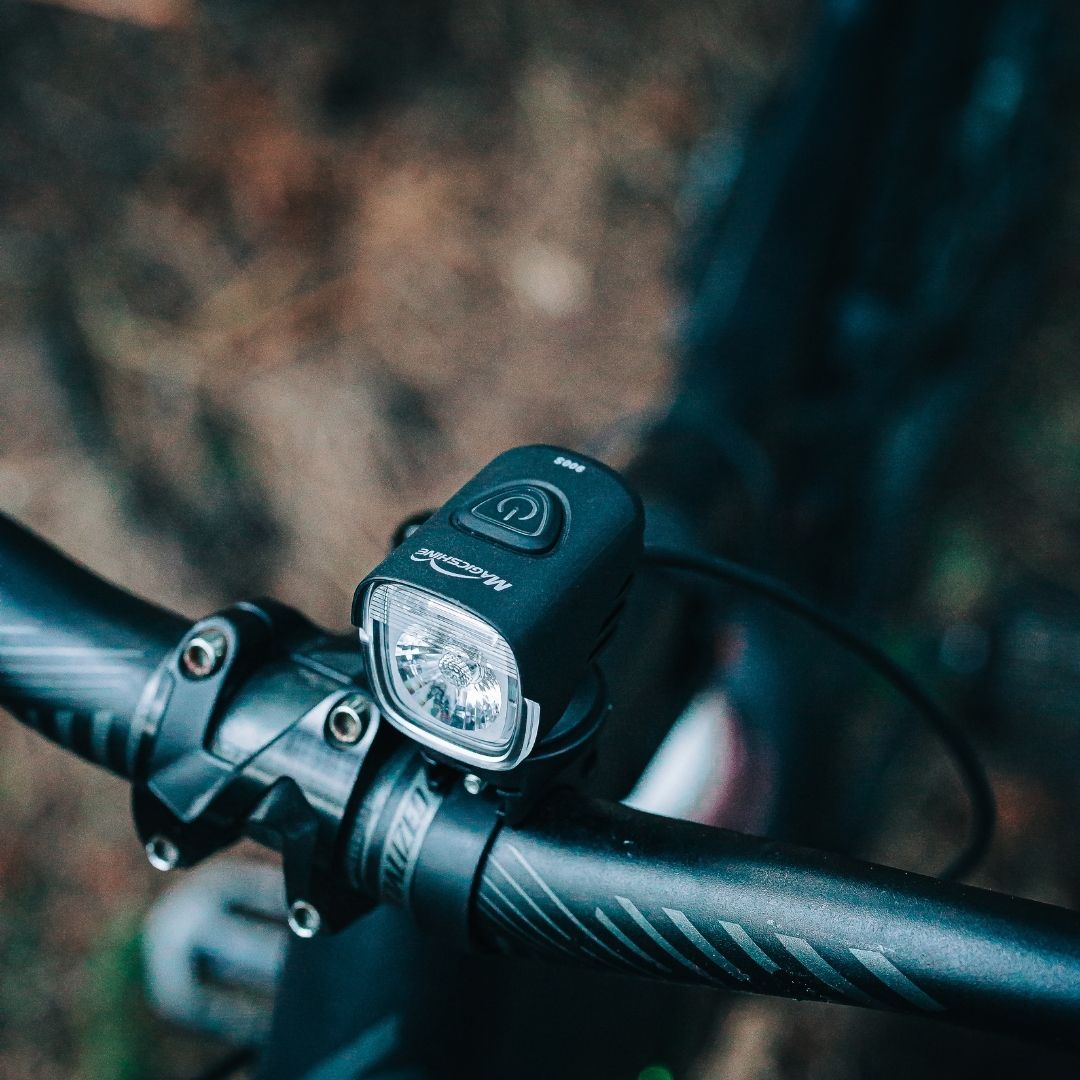 Magicshine MJ-906S nasadené na riadidlách horského bicykla za denného svetla, z tela vedie napájací kábel