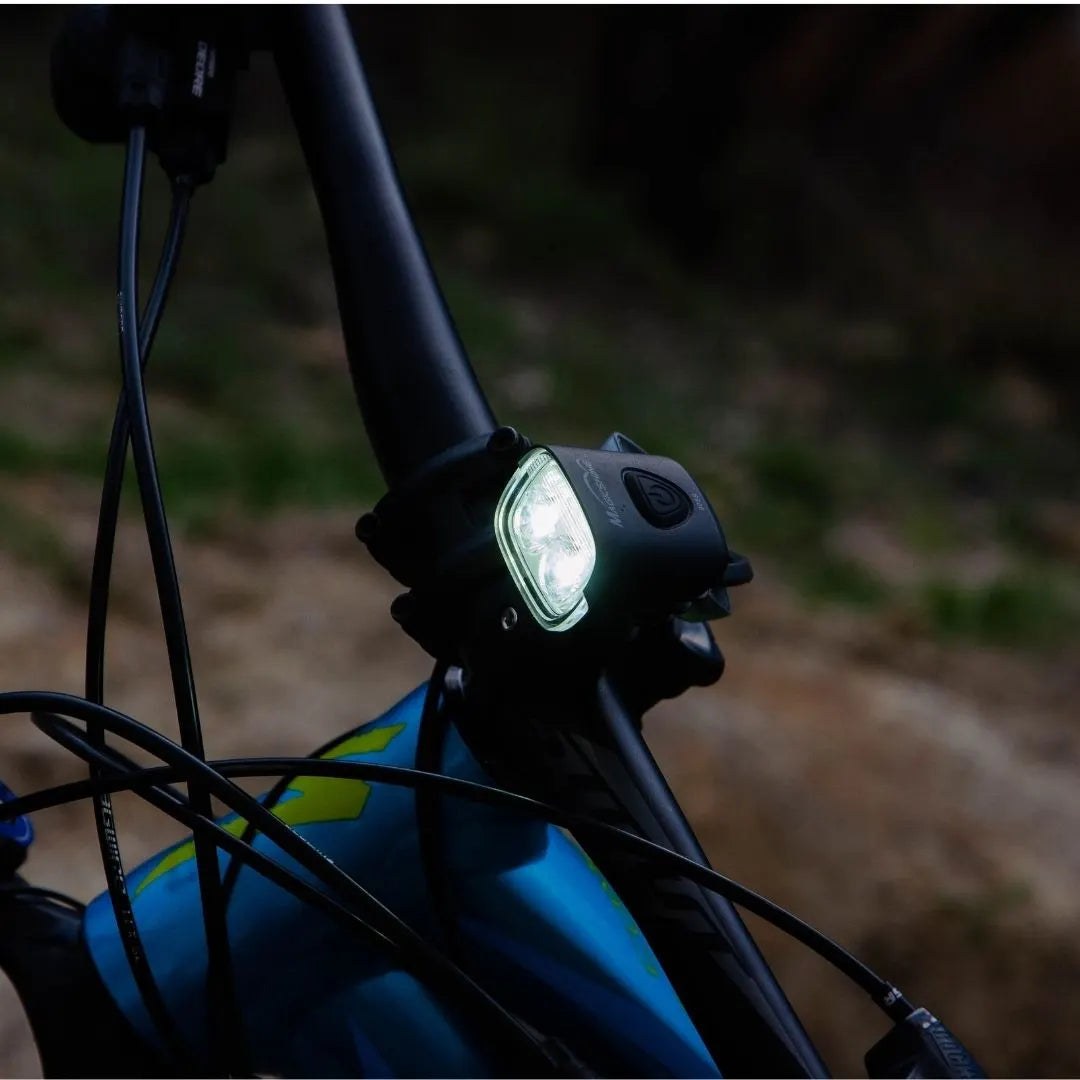 Rozsvietené svetlo Magicshine MJ-906S na riadidlách bicykla v tme, vidno obe hlavné LED aj svetlo unikajúce do strán