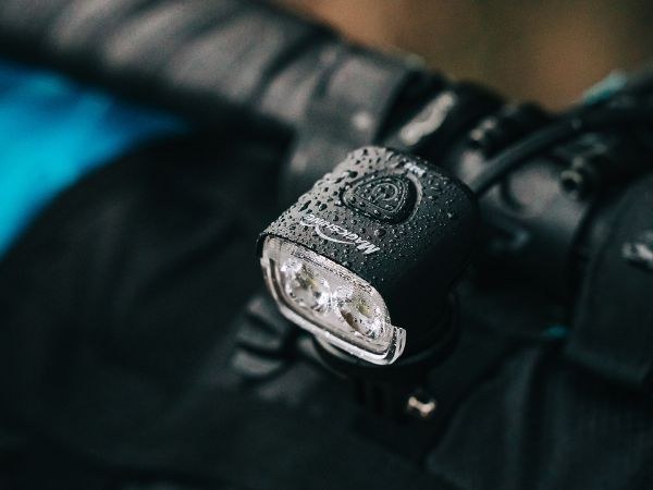 Magicshine MJ-906S na riadidlách pokryté kvapkami vody &mdash; detail dvoch šošoviek a tlačidla po daždi