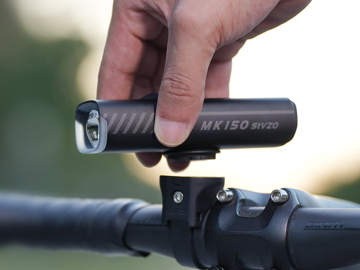 Ruka nasadzuje Magicshine MK 150 StVZO do držiaka na riadidl&aacute;ch cestn&eacute;ho bicykla