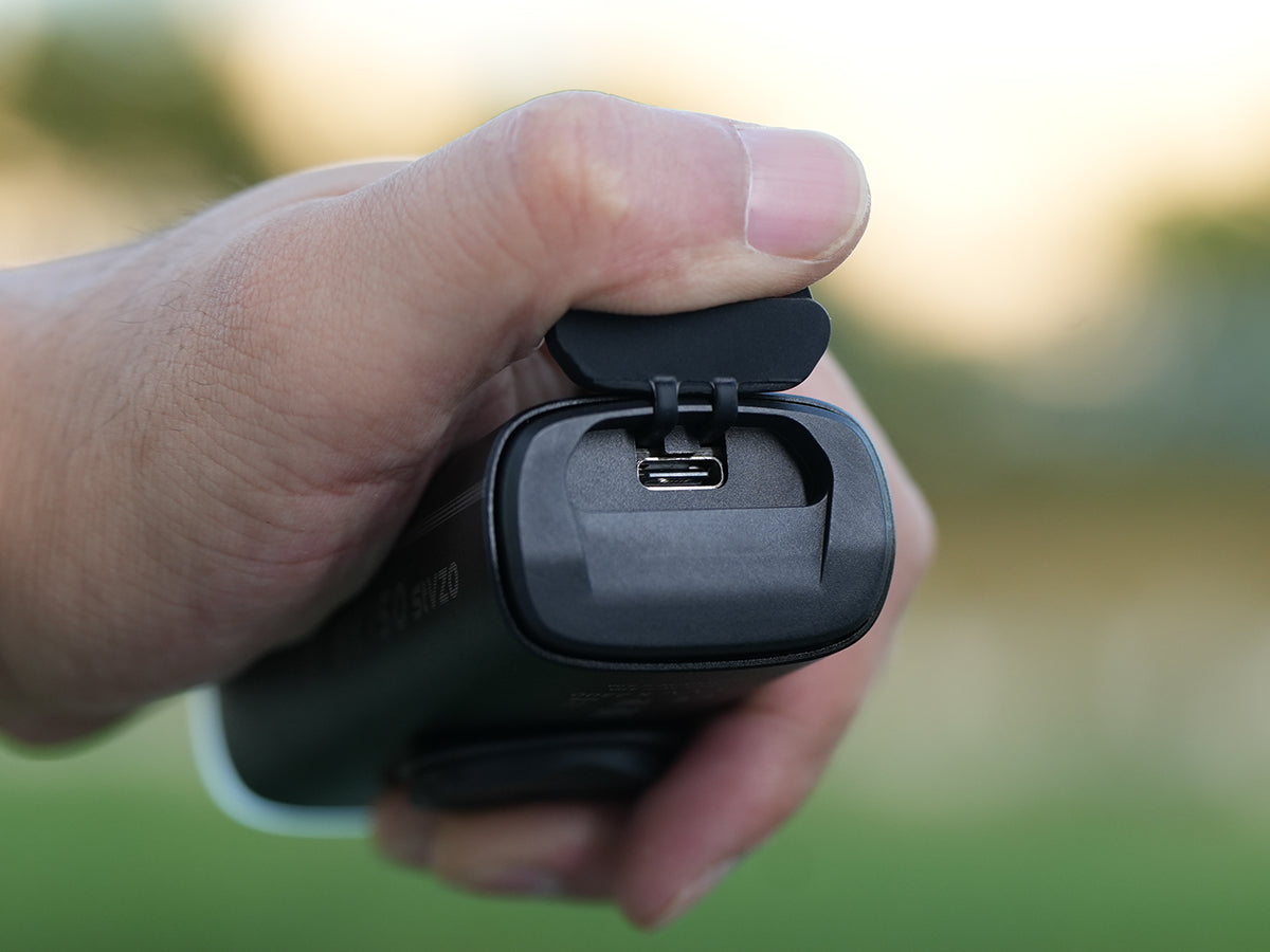 Odklopen&yacute; gumen&yacute; kryt a port USB-C na tele Magicshine MK 150 StVZO držan&eacute;ho v ruke