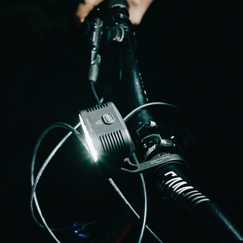 Magicshine Monteer 6500S V2.0 svieti v noci na riadidlách horského bicykla, telo svetla je zboku takmer neviditeľné