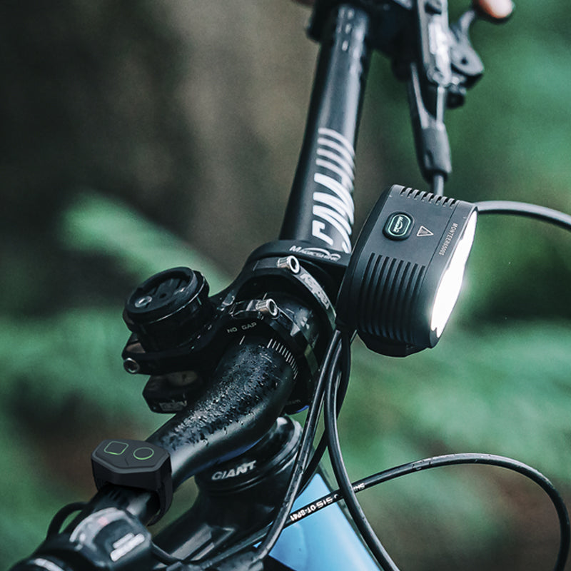 Magicshine Monteer 6500S V2.0 na predstavci horského bicykla a jeho bezdrôtový ovládač pripnutý na riadidlách pri páke