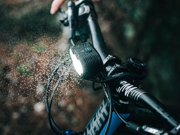 Rozsvietené svetlo Magicshine Monteer 6500S V2.0 na riadidlách horského bicykla v spŕške vody