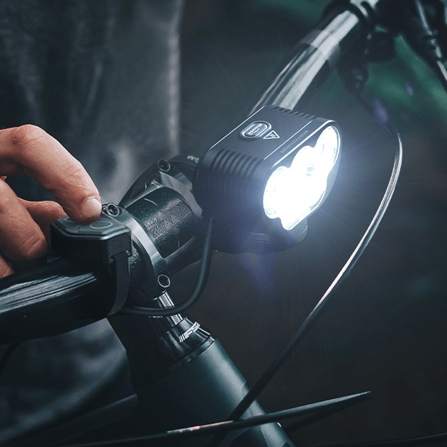 Detail rozsvieteného MONTEER 8000S V2.0 na riadidlách horského bicykla počas nočnej jazdy