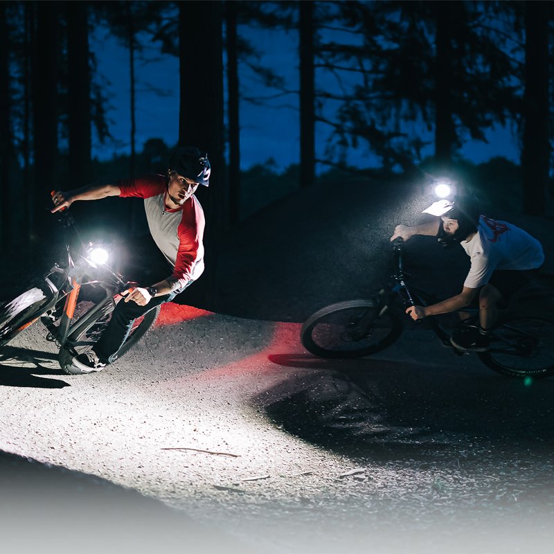 Dvaja cyklisti na nočnom traili, predné svetlá MONTEER 8000S V2.0 osvetľujú štrkovú cestu pred nimi