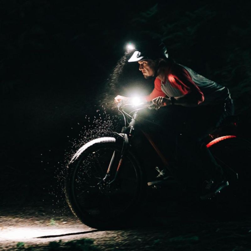 Magicshine MONTEER 8000S V2.0 osvetľuje nočný terén — jazdec na horskom bicykli vo zvírenom prachu