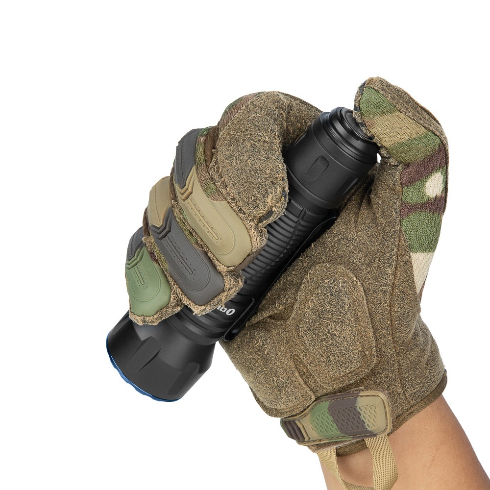 Olight Javelot Long Matte Black v maskáčovej taktickej rukavici – rukoväť v dlani, hlava s modrým lemom dole