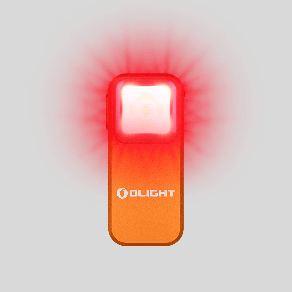 Olight Oclip Orange svieti načerveno, okolo hlavy svetla sa rozlieva sýto červená žiara nad oranžovým telom