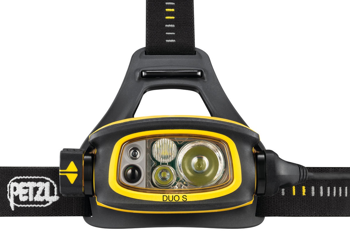 Petzl DUO S — čelný pohľad na optiky čelovky v žltom ráme: hranatá vrúbkovaná šošovka, dve menšie okrúhle optiky a veľký reflektor, vedľa nich okienko s kontrolkou vybitia