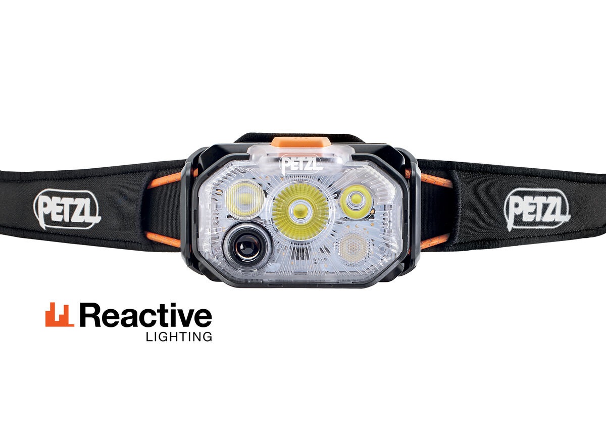 Petzl SWIFT RL — čelný pohľad na priehľadnú optiku so zmiešaným lúčom, tmavým okienkom senzora okolitého svetla a oranžovým tlačidlom