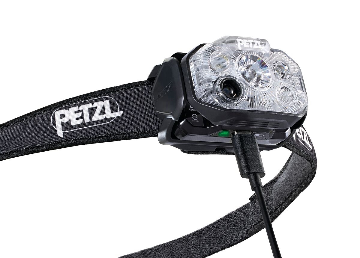 Petzl SWIFT RL CLASSIC — telo čelovky so širokým čiernym pásikom, do konektora je zapojený USB-C kábel a svieti zelený indikátor nabitia