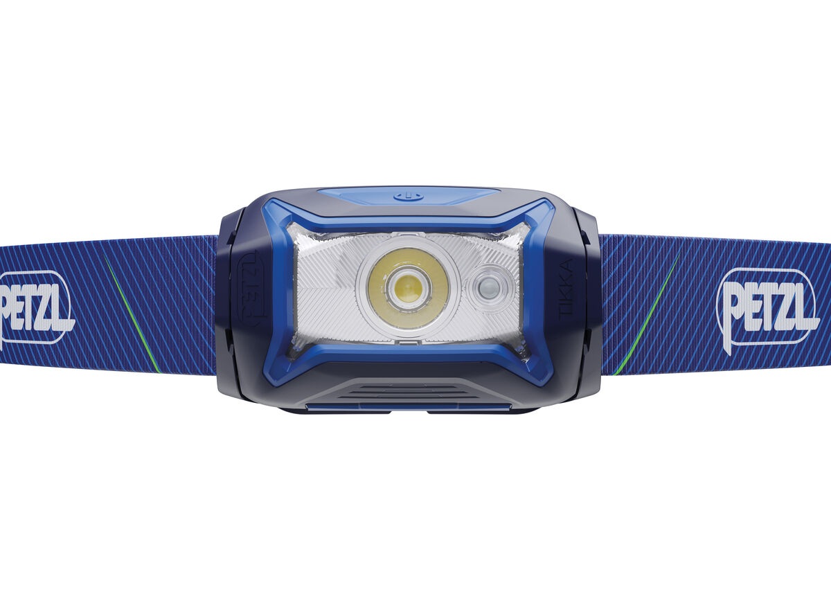 Petzl TIKKA zblízka spredu — v priehľadnej optike jedna veľká biela LED a vedľa nej menšia červená LED, hore ovládacie tlačidlo