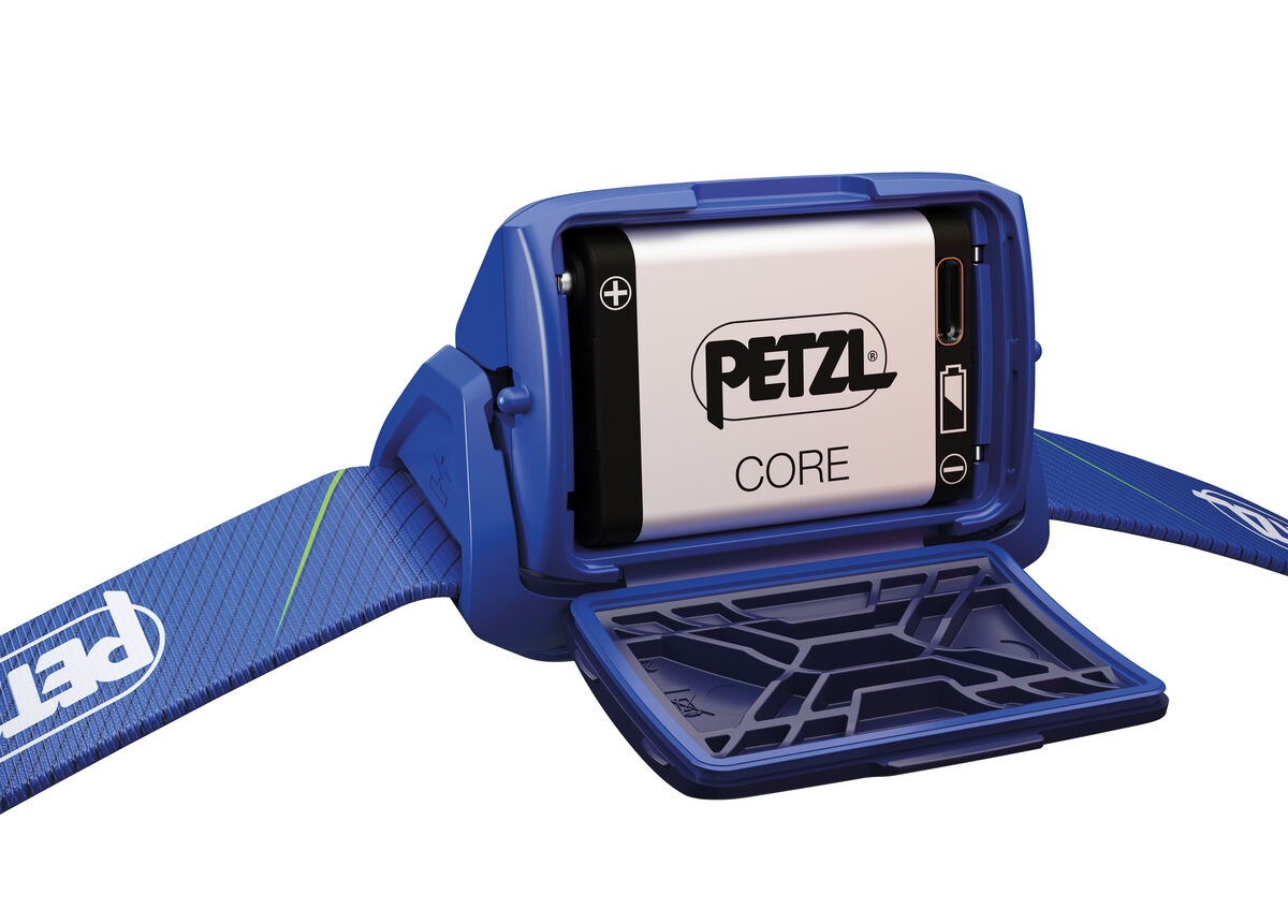 Petzl TIKKA CORE s otvoreným batériovým boxom — vnútri vložený strieborný nabíjateľný článok Petzl CORE s portom USB-C a značkami plus a mínus